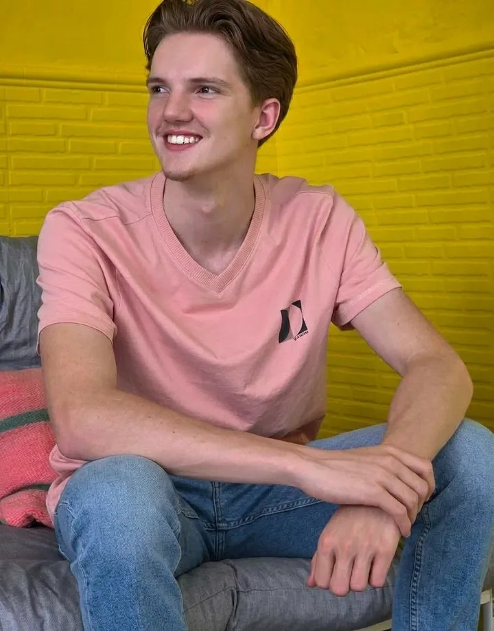 Kaj Put, lachend op een bank voor een gele muur